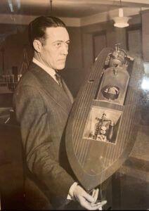 Man in a suit holding a model boat, historic photo, large