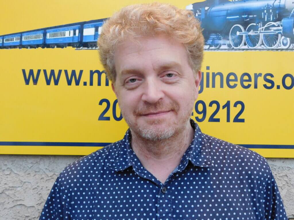 Club member with curly hair in a patterned shirt