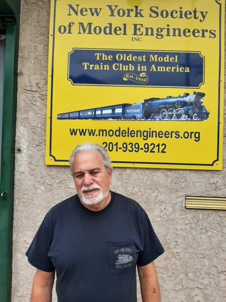 Club member in a black T-shirt by the clubhouse sign